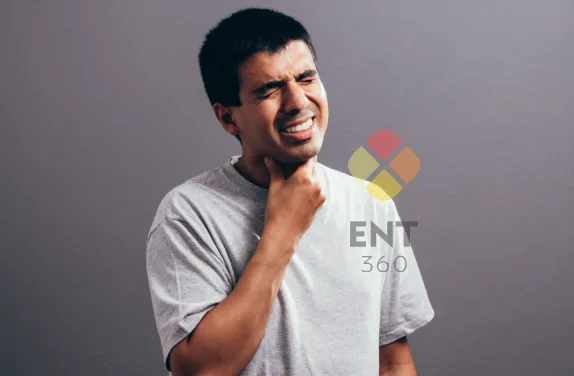 A man holding his throat, seems to be in pain or discomfort, could be due to hoarseness or pain.